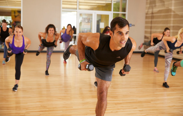 group of people wearing workout clothes holding weights and leaning forward