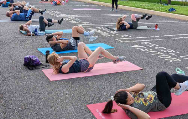people laying on mats in parking lot doing crunches