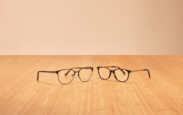 two pairs of eye glasses on wooden surface