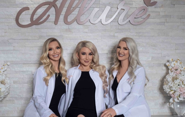 Three women seated in front of a sign that says Allure